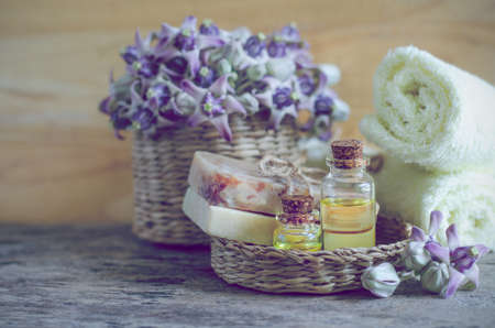 Close up agroma gel in glass bottle with soap in wooden basket with soft yellow and purple fragrance flower on wooden background in spa shop, ready for health careの写真素材