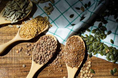 Four kinds of natural cereal and grain seed in wooden spoon consisted of pumpkin seed, flax seed,...