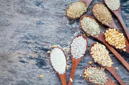 Variety kinds of natural cereal and grain seeds in wooden spoon on grunge background, for healthy or...