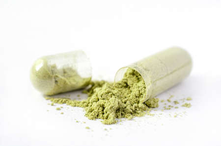 Closed up green Thai herb powder in capsule on white background. For natural medication or...