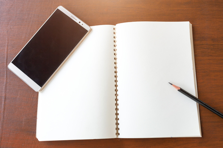 Blank note book with pencil and smartphone on wooden table background concept and Idea for write your text here.の写真素材
