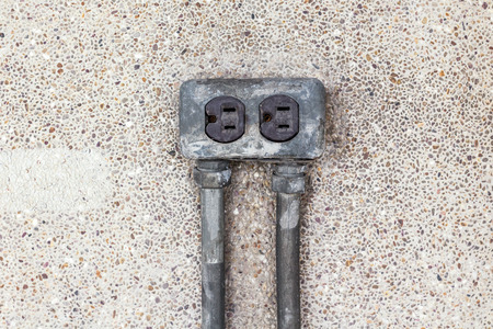 Asia plug socket on brick wall background. Risk of danger.