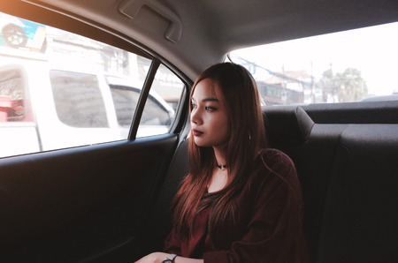 Beautiful young woman is sitting on back seat in the car.Dark tone with film grain.
