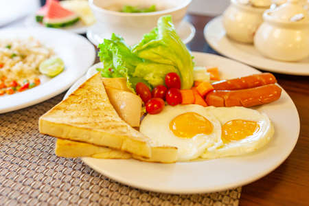 Full American Breakfast on dark, top view, banner. Sunny side fried eggs, roasted bacon, hash brown and toastsの写真素材