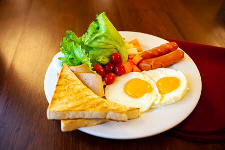 Full American Breakfast on dark, top view, banner. Sunny side fried eggs, roasted bacon, hash brown and toastsの写真素材