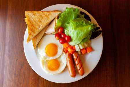 Full American Breakfast on dark, top view, banner. Sunny side fried eggs, roasted bacon, hash brown and toastsの写真素材