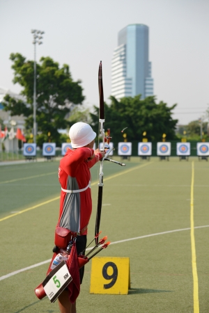 An archer with bow takes aim at a target during competitionの写真素材