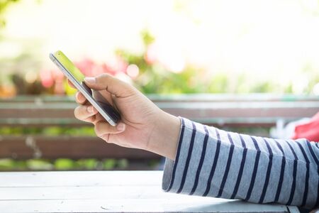 A male(man) hand hold(touch) and looking at smart phone  in the park