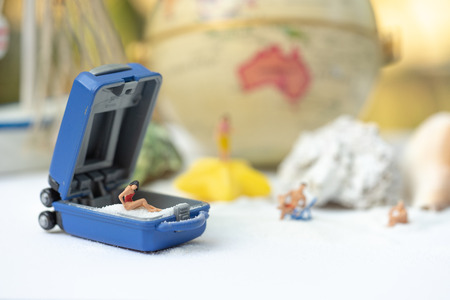 Miniature people, travelers relaxing on the sand box decorating in summer theme using as background...
