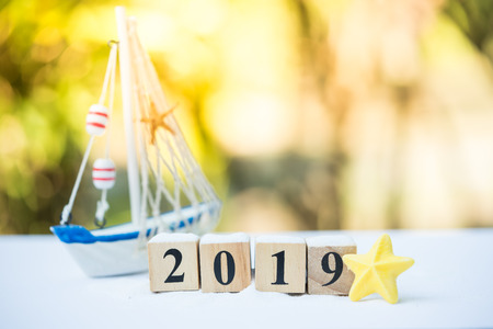 Traveling in summer concept. The 2019 wooden blocks on summer decoration sandbox with world globe...
