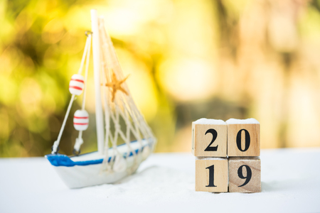 Traveling in summer concept. The 2019 wooden blocks on summer decoration sandbox with world globe and travel stuffs.の写真素材