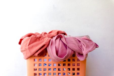 Clothes that have already been worn and placed in a basket are waiting to be washed, with the main scene being white.の写真素材