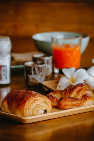 Bread and croissants in a tray with fruit juice set in the background.の写真素材