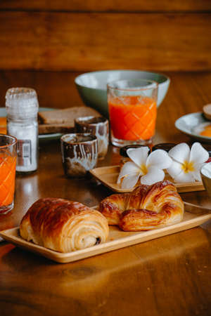 Bread and croissants in a tray with fruit juice set in the background.の写真素材