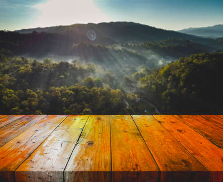 An old wooden table with a mountain and fog backdrop.の写真素材