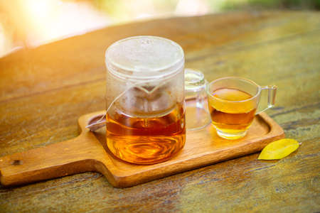 Teapots and glasses are placed on wooden trays with a natural backdrop.の写真素材