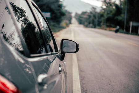 An image of a car's rearview mirror with raindrops taken from the side of the car.の写真素材