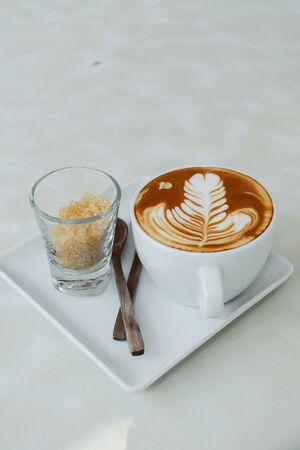 Hot latte and sugar on the white tableの写真素材