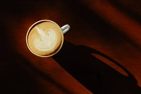 Coffee cup with latte art on the wood table