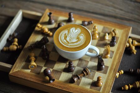 Coffee cup with latte art on the chessboardの写真素材