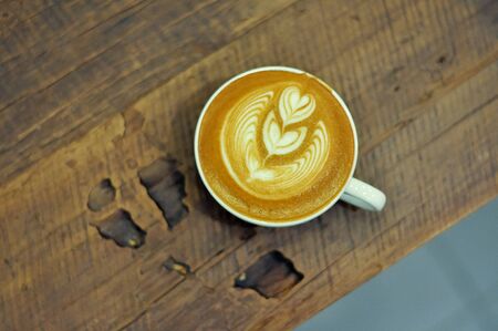 Coffee cup with latte art on the wood tableの写真素材