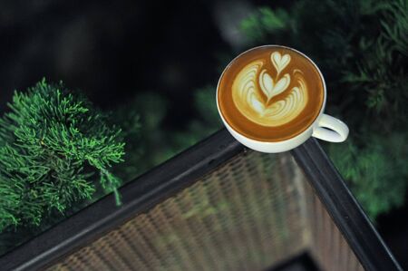Coffee cup with latte art on the metal fenceの写真素材