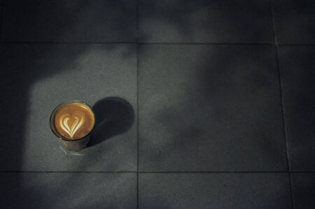 Coffee cup with latte art on the floor with the abstract shadow.の写真素材