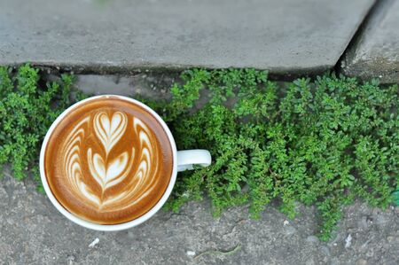 Coffee cup with latte art on the concrete floor.の写真素材