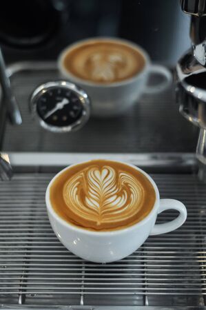 Coffee cup with latte art on the espresso machine tray.の写真素材