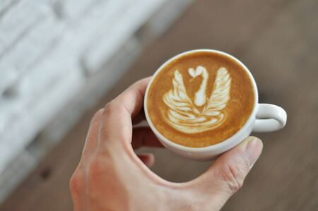 Barista hand holding cup of coffee with his latte art.の写真素材