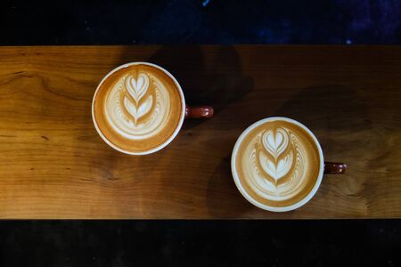 Coffee cup with latte art on the wood table.