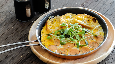 breakfast: fried eggs with croissants and sausage in pan on wood tableの写真素材