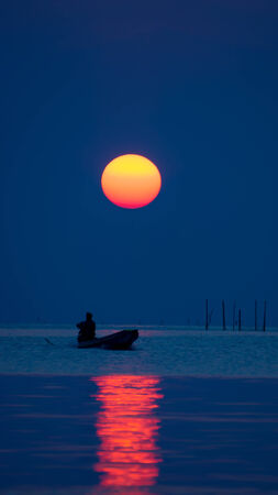 Silhouettes fisherman and sunset on the lake.の写真素材