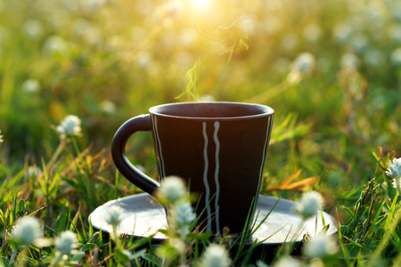 morning coffee with black cup in the flower grass background.の写真素材