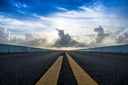 Empty road and the yellow traffic lines with clouds.の写真素材