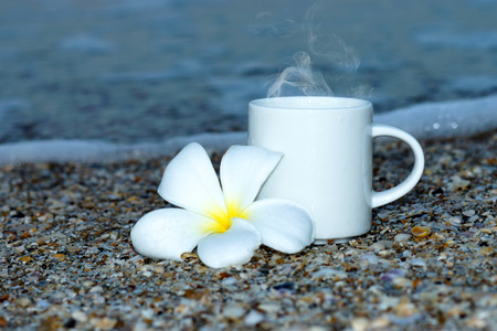 coffee cup and frangipani flowers on the beachの写真素材