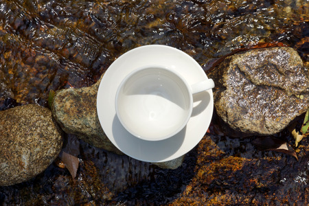 White coffee cup on the rocks at the waterfalls.の写真素材