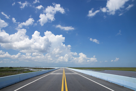 Empty road and the yellow traffic lines with blue sky.の写真素材