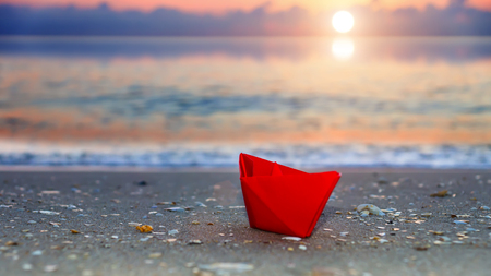 Red paper boats on beach outdoors.の写真素材
