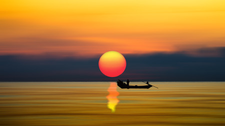 Silhouettes of Minimal fisherman at the sea and big sun.の写真素材
