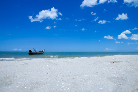Fishing boat on the beach with blue sky and sand.