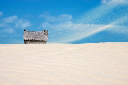 Fisherman's hut on the beach with sandstorm and blue sky.の写真素材