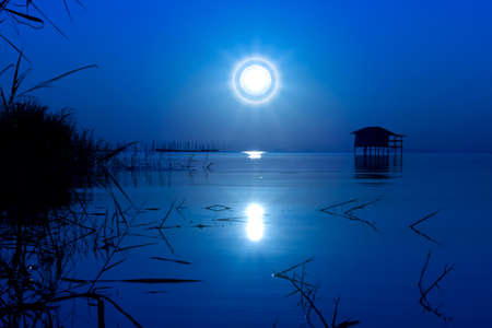 Moonset in blue sky on the lake., un-focus image.の写真素材
