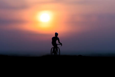 Silhouettes cyclists on the beach at sunset.の写真素材