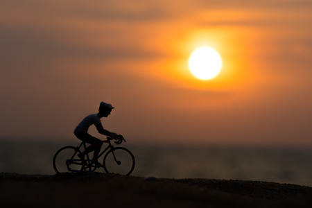 Silhouettes cyclists on the beach at sunset.の写真素材