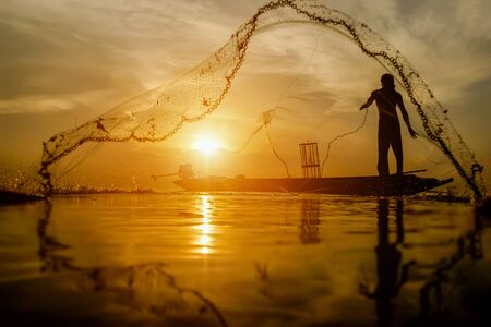 silhouette fisherman with sunset sky on the lake.