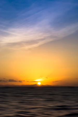 Beautiful sunset at the lake with saturated sky and clouds. Idea: Un-focus image and use for background.の写真素材
