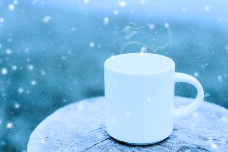White coffee mug in the winter with snow fall.の写真素材