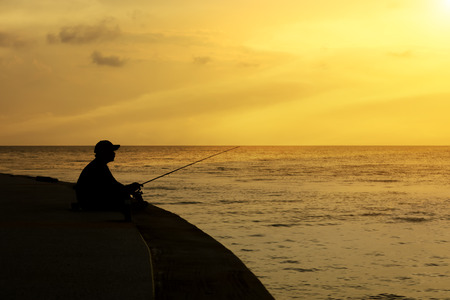 Silhouette of man fishing on a lake.の写真素材