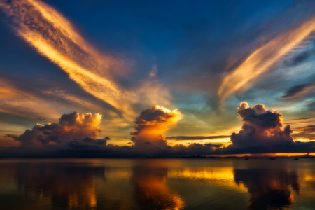 Beautiful smooth and bright yellow clouds over the dark lake after sunset.